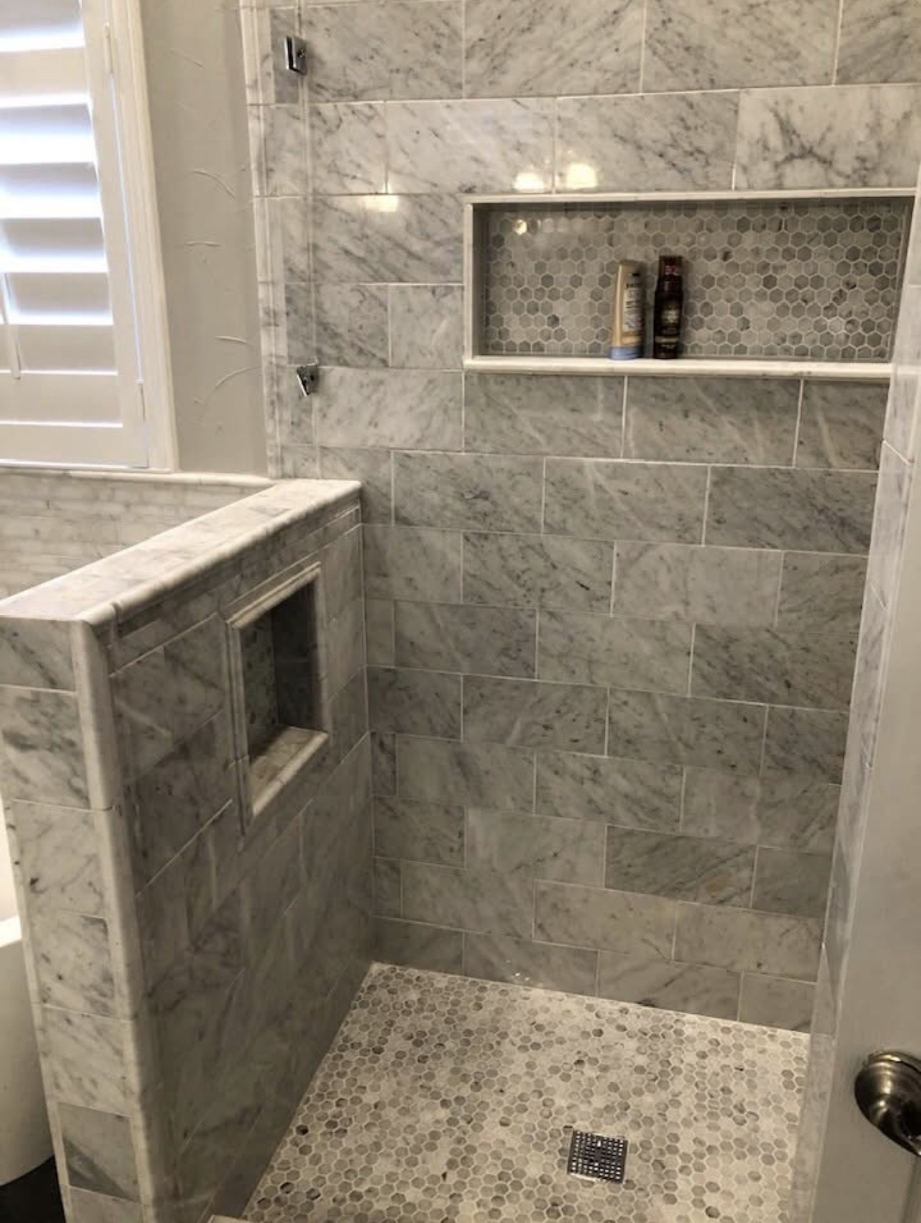 Calacatta marble walk-in shower with built-in bench and mosaic niche — Fort Worth TX